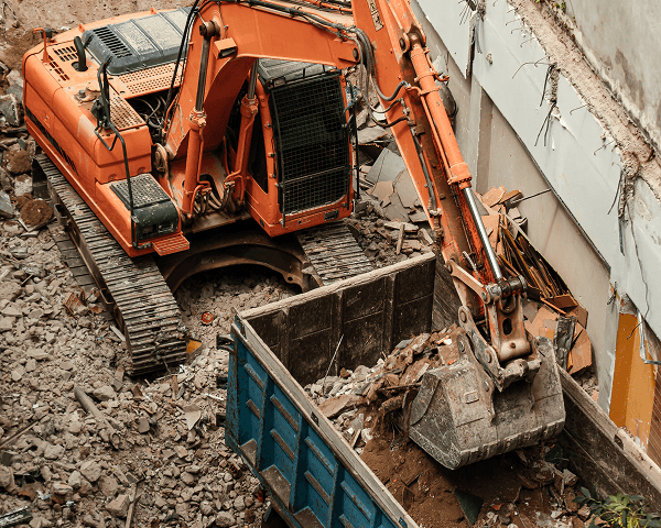 Abbrucharbeiten – Bagger verlädt Bauschutt auf Anhänger