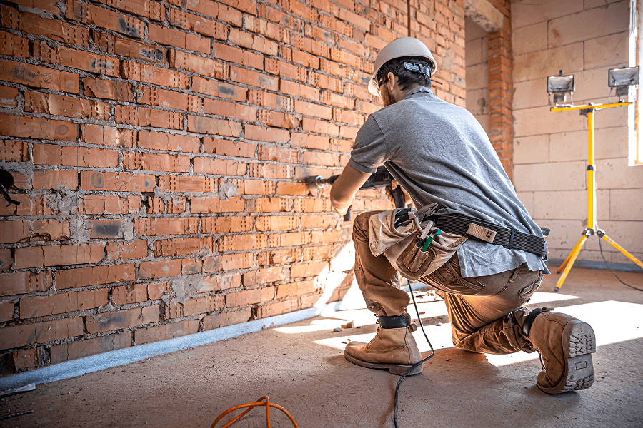 Mauerwerksarbeiten – Handwerker beim Verputzen der Ziegelwand